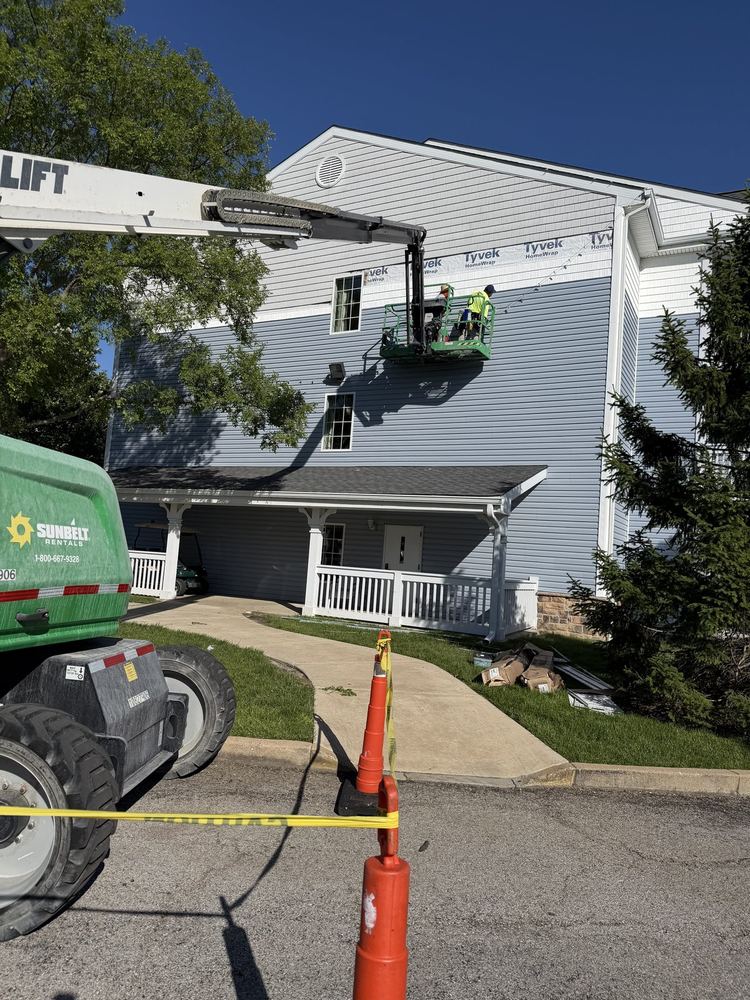 Amigo crew on a boom lift installing siding over Tyvek wrap on a multi-story building