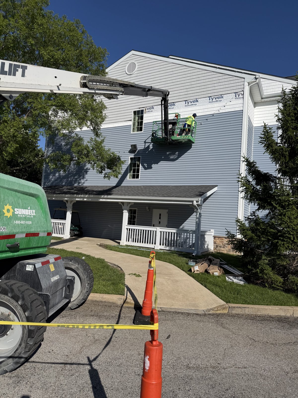 Amigo crew on a boom lift installing siding over Tyvek wrap on a multi-story building